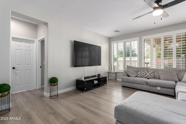 living area featuring light wood finished floors, baseboards, a ceiling fan, and visible vents