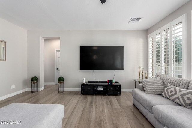 living area with visible vents, baseboards, and wood finished floors