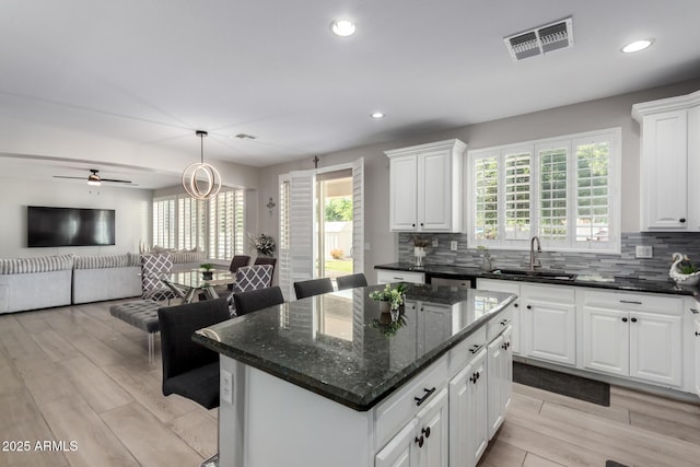 kitchen with a center island, a healthy amount of sunlight, a sink, and visible vents