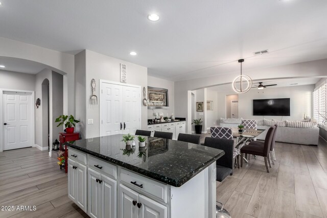 kitchen featuring open floor plan, white cabinets, arched walkways, and a ceiling fan