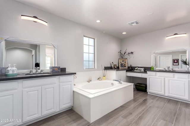 full bathroom with two vanities, wood finished floors, and a sink
