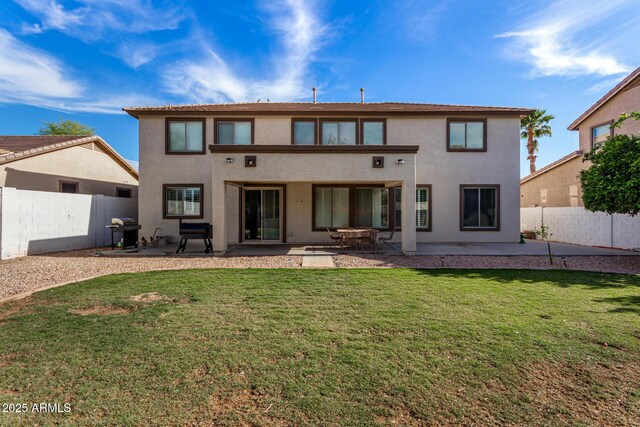 rear view of property with stucco siding, a fenced backyard, a yard, and a patio
