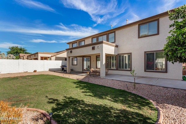 back of house with stucco siding, fence, a patio area, and a lawn