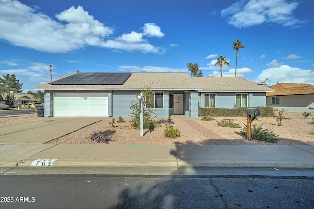 ranch-style home featuring a garage and solar panels