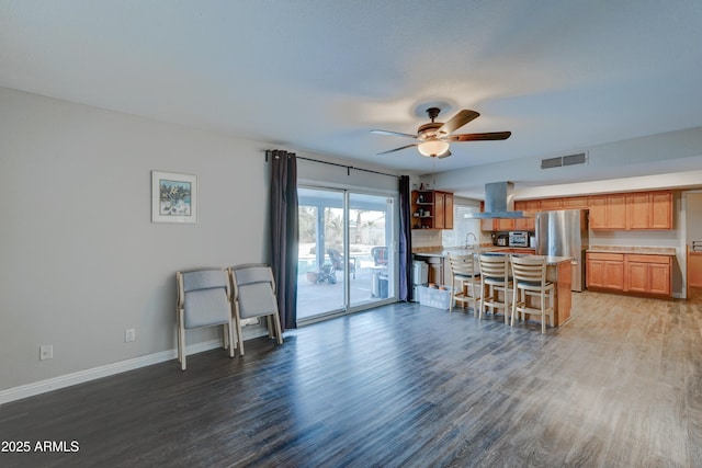 kitchen with sink, stainless steel fridge, a breakfast bar, dark hardwood / wood-style floors, and island exhaust hood