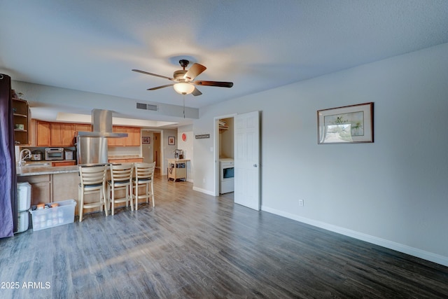 kitchen featuring a kitchen bar, sink, island range hood, dark hardwood / wood-style flooring, and ceiling fan