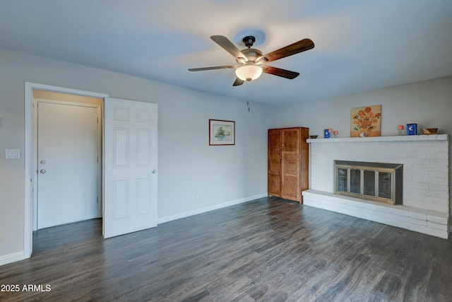 unfurnished living room with a brick fireplace, dark hardwood / wood-style floors, and ceiling fan