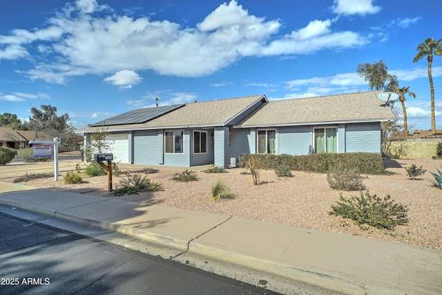 ranch-style house with a garage and solar panels