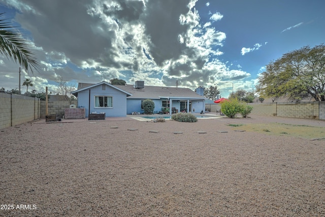 rear view of house with a fenced in pool, central air condition unit, and a patio area