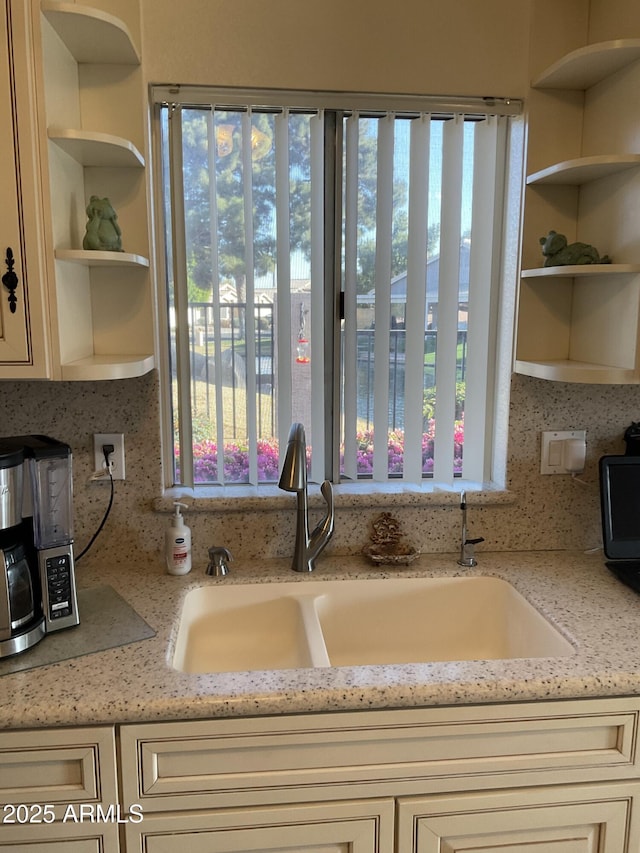 kitchen featuring plenty of natural light, light stone countertops, sink, and decorative backsplash