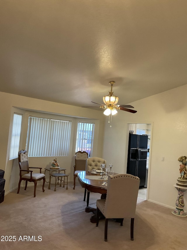 carpeted dining room with ceiling fan