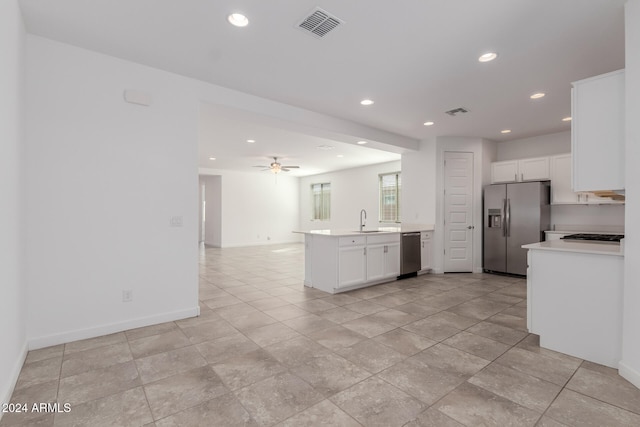 kitchen with kitchen peninsula, white cabinets, ceiling fan, sink, and stainless steel appliances