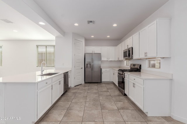 kitchen featuring appliances with stainless steel finishes, white cabinets, sink, and light tile patterned floors