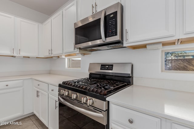 kitchen with appliances with stainless steel finishes, white cabinets, and light tile patterned flooring