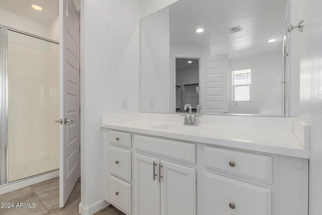 bathroom featuring a shower with door, vanity, and tile patterned floors