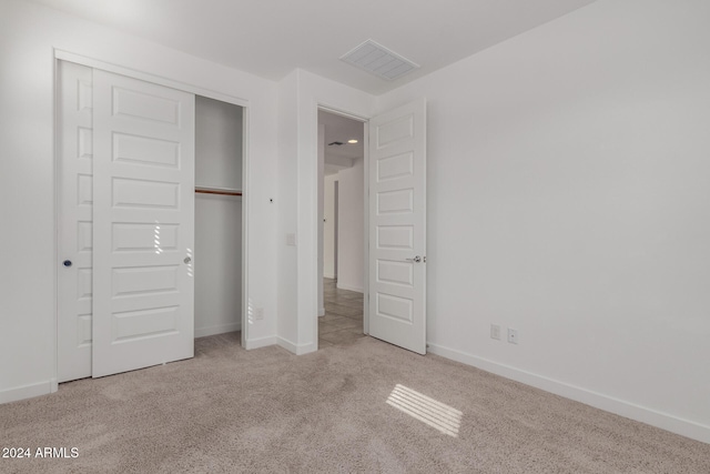 unfurnished bedroom featuring a closet and light carpet