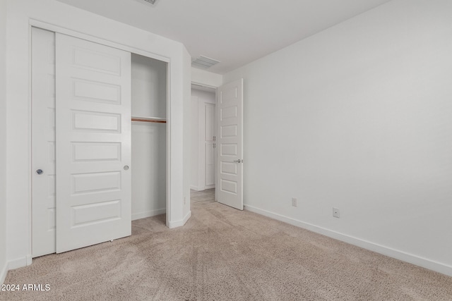 unfurnished bedroom with a closet and light colored carpet