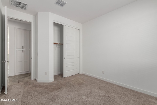 unfurnished bedroom with a closet and light carpet