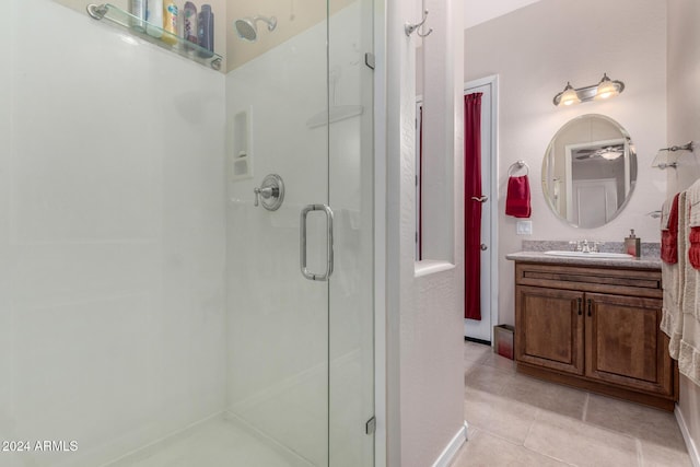 bathroom with a shower with door, vanity, and tile patterned flooring