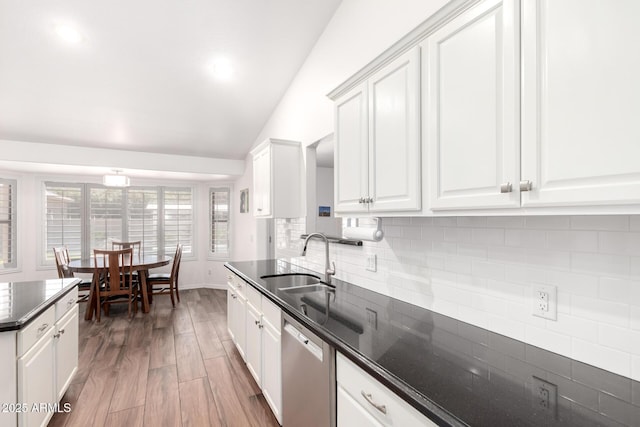 kitchen with wood finished floors, a sink, white cabinetry, decorative backsplash, and dishwasher