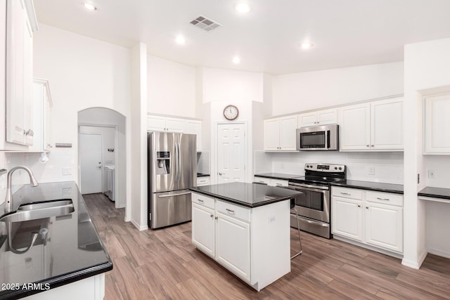 kitchen featuring stainless steel appliances, dark countertops, a sink, and visible vents