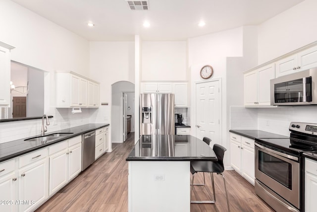 kitchen featuring appliances with stainless steel finishes, dark countertops, visible vents, and a sink