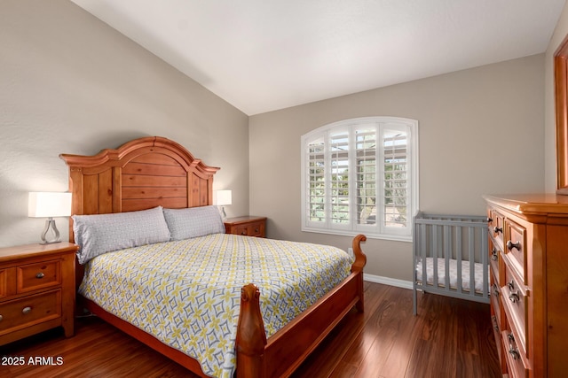 bedroom featuring lofted ceiling, dark wood finished floors, and baseboards