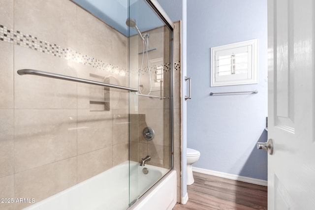 full bathroom featuring toilet, baseboards, combined bath / shower with glass door, and wood finished floors