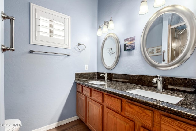 bathroom with double vanity, wood finished floors, a sink, and toilet