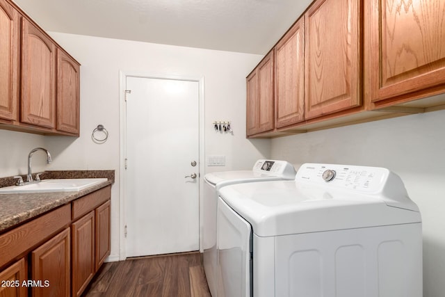 washroom with dark wood-style floors, independent washer and dryer, cabinet space, and a sink