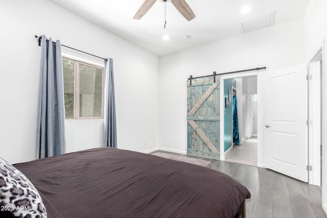 bedroom with a barn door, attic access, ceiling fan, wood finished floors, and recessed lighting