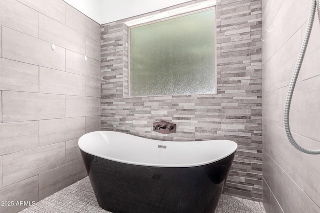 full bath featuring a freestanding tub and tile walls