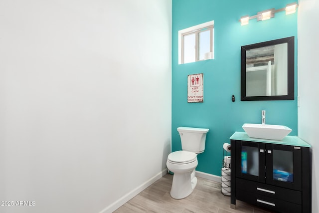 bathroom featuring baseboards, vanity, toilet, and wood finished floors