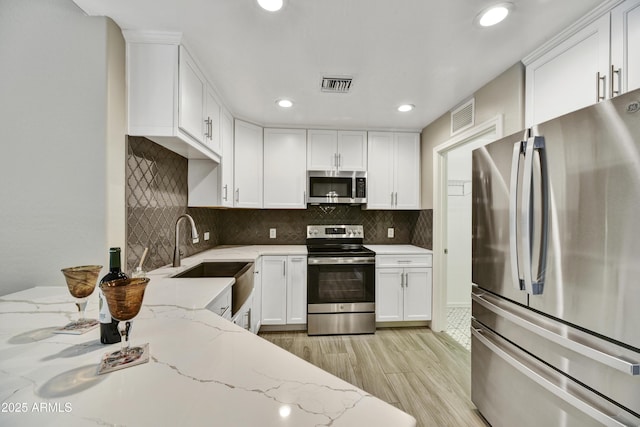 16 W Encanto Blvd Unit 22, Phoenix, AZ 85003 - kitchen with stainless steel appliances, a sink, light wood finished floors, white cabinetry, and light stone counters
