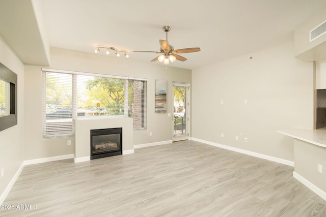 16 W Encanto Blvd Unit 22, Phoenix, AZ 85003 - unfurnished living room with a glass covered fireplace, a ceiling fan, plenty of natural light, and light wood-style flooring