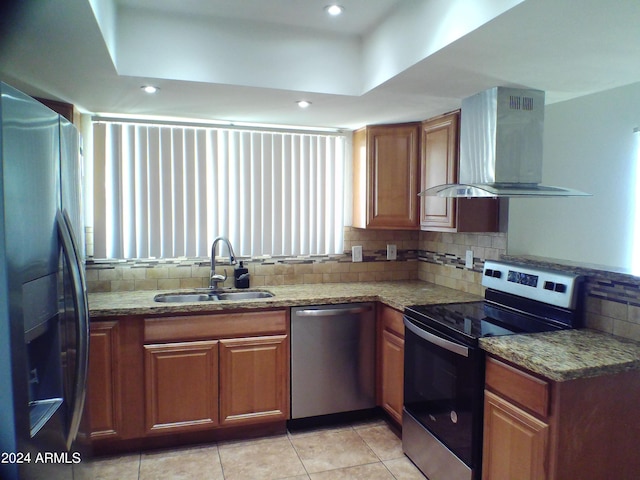 kitchen with light stone countertops, sink, stainless steel appliances, wall chimney range hood, and tasteful backsplash