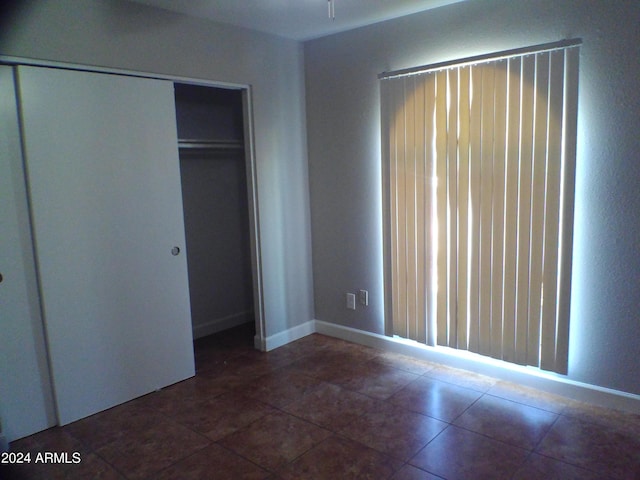 unfurnished bedroom featuring dark tile patterned floors and a closet