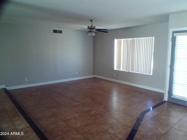 empty room featuring dark tile patterned flooring and ceiling fan