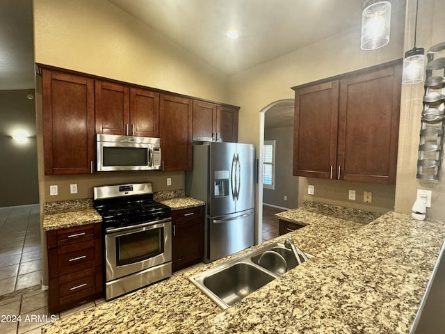 kitchen with lofted ceiling, hanging light fixtures, sink, appliances with stainless steel finishes, and kitchen peninsula