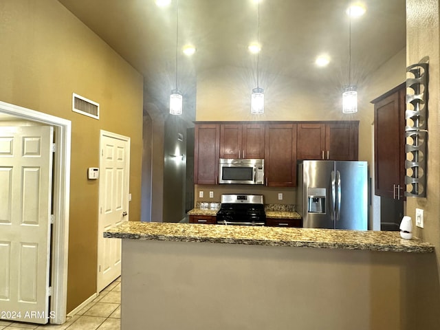 kitchen with light stone counters, light tile patterned floors, stainless steel appliances, and decorative light fixtures