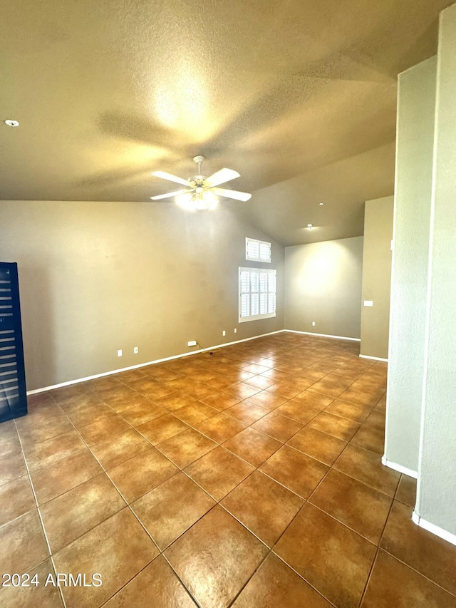 tiled spare room featuring a textured ceiling, ceiling fan, and lofted ceiling