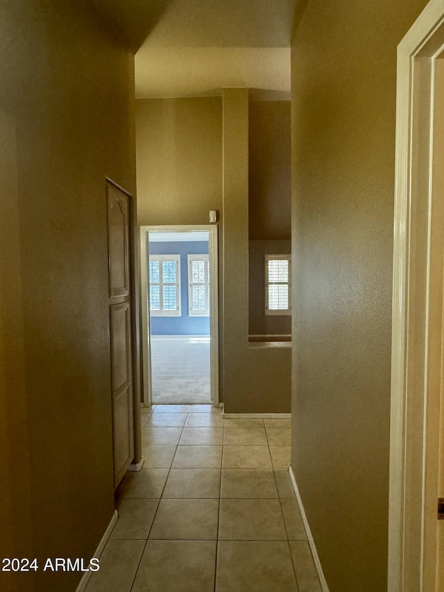 hallway with light tile patterned floors and a towering ceiling