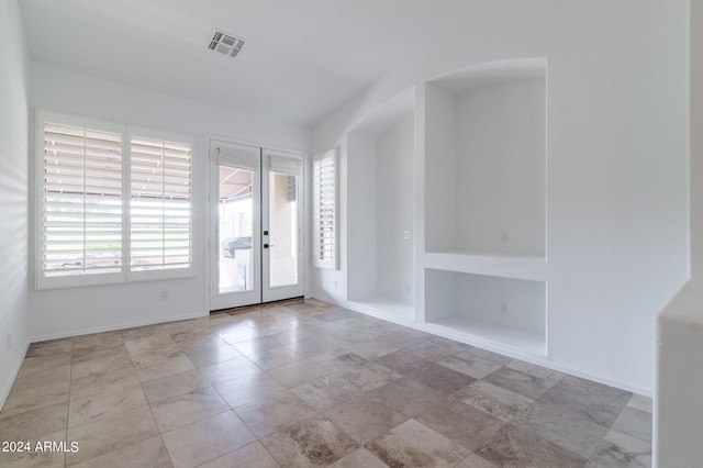 unfurnished room featuring built in features and french doors