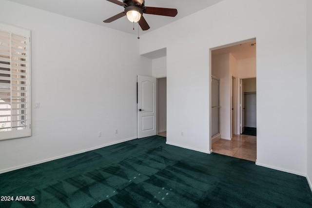 unfurnished bedroom with a closet, dark colored carpet, and ceiling fan