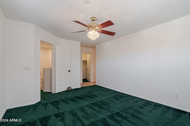 spare room with ceiling fan and dark carpet