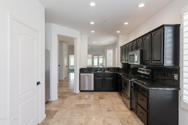 kitchen featuring light tile patterned floors, sink, backsplash, stainless steel appliances, and dark stone countertops