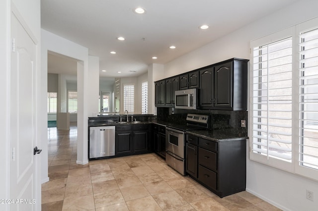 kitchen featuring dark stone countertops, appliances with stainless steel finishes, tasteful backsplash, and a healthy amount of sunlight