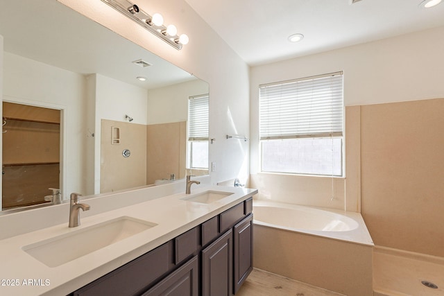 bathroom with plus walk in shower, plenty of natural light, and vanity