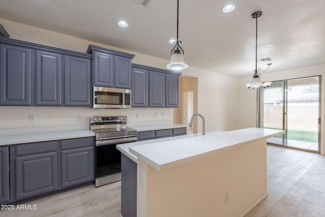 kitchen with stainless steel appliances, a center island with sink, light hardwood / wood-style flooring, a chandelier, and hanging light fixtures