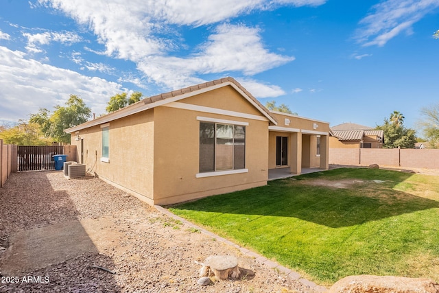 back of property with central AC unit and a yard